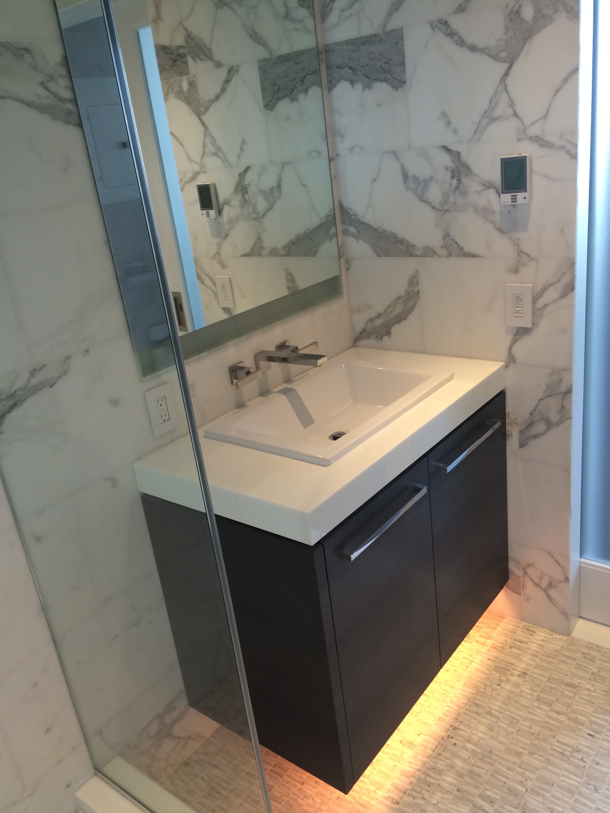 Modern bathroom vanity with marble walls and mirror